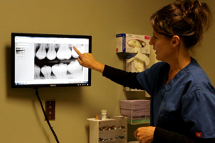 A dentist from Alan B. Evans, DDS, PC in Muscatine, IA points out something on an X-Ray of a patients mouth