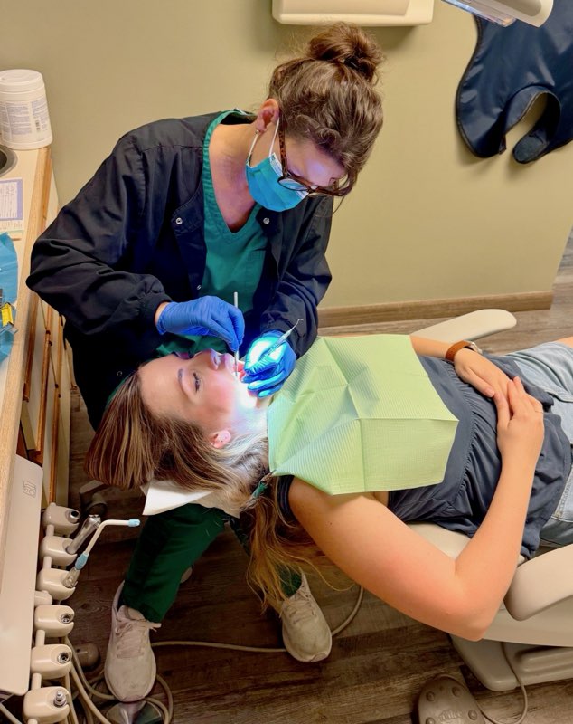 Dentists from Alan B. Evans, DDS, PC in Muscatine, IA working on a patients mouth while laying down in the dentist chair